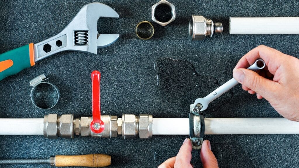 Plumber repairing a pipe valve with an adjustable wrench in Fort Myers