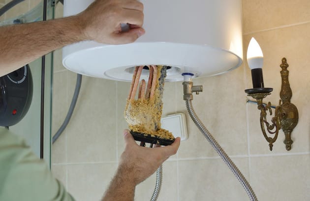 Technician removing mineral buildup from a water heater in Fort Myers